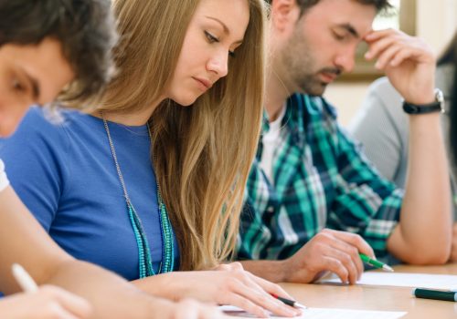 Students having a test in a classroom (adapted) (Image by luckybusiness via AdobeStock)