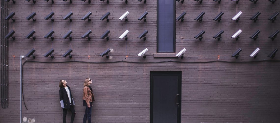 Women look at security cameras (adapted) (Image by Matthew Henry [CC0 Public Domain] via Unsplash)