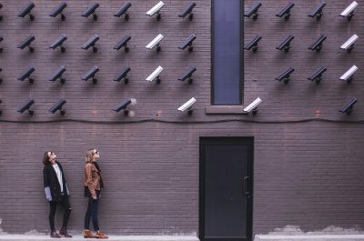 Women look at security cameras (adapted) (Image by Matthew Henry [CC0 Public Domain] via Unsplash)