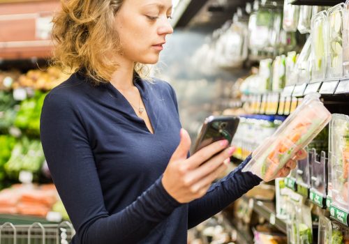 Young woman shopping in the fresh produce section at the grocery store.