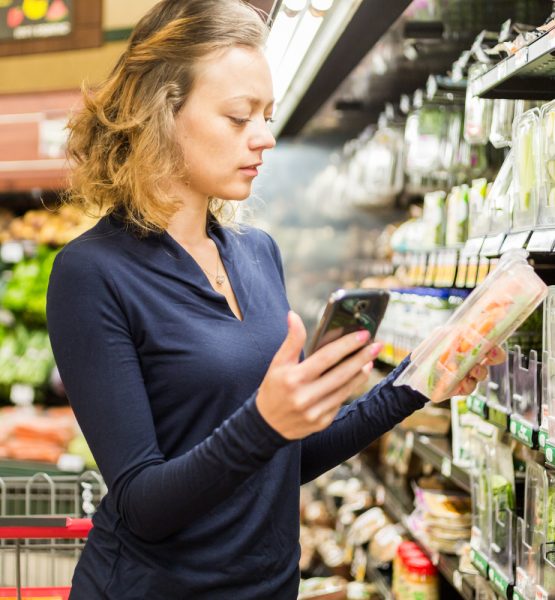 Young woman shopping in the fresh produce section at the grocery store.