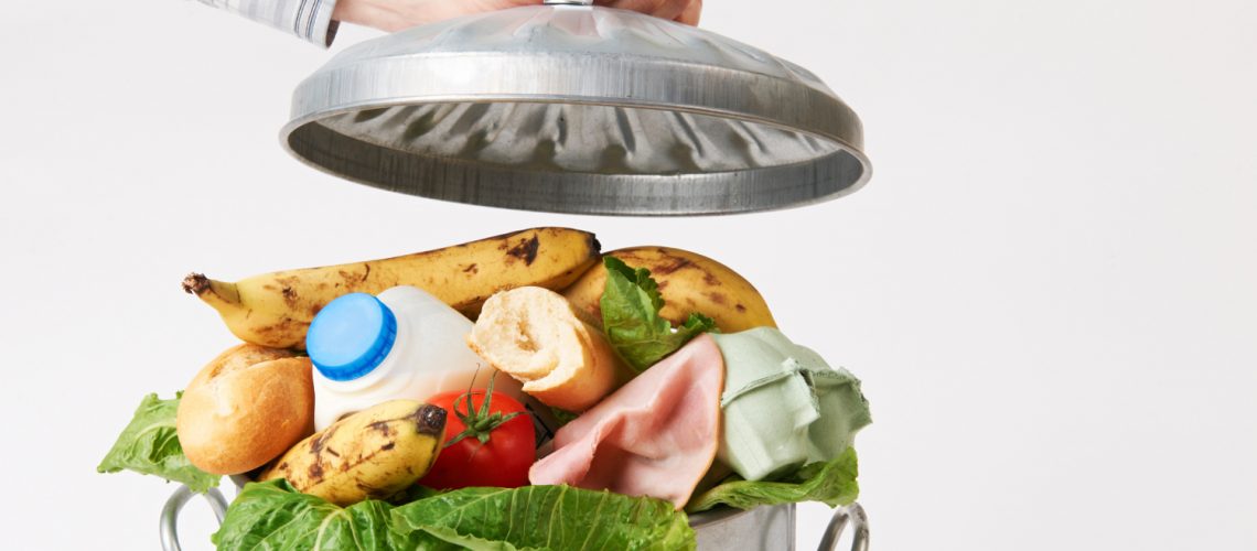 Hand Putting Lid On Garbage Can Full Of Waste Food