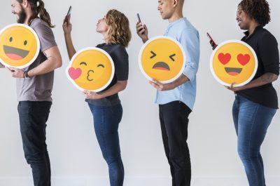 4 junge Menschen mit Emojis und Smartphones.