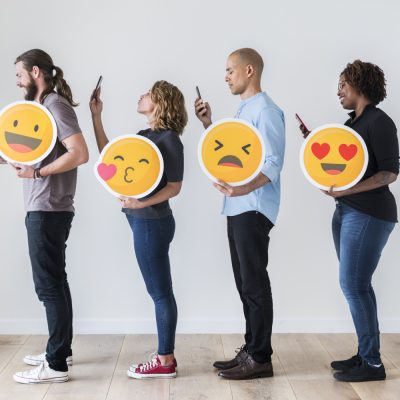 4 junge Menschen mit Emojis und Smartphones.