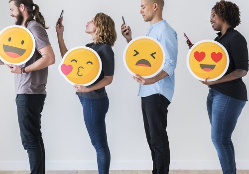 4 junge Menschen mit Emojis und Smartphones.