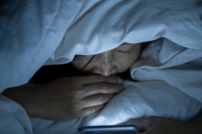 Eine Frau mit Smartphone im Bett