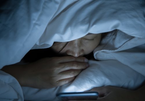 Eine Frau mit Smartphone im Bett