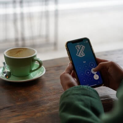Die besten Sprachlern-Apps Titelbild - Kaffeetasse uns Person am Smartphone / Bild von Ashley Whitlatch via unsplash.com