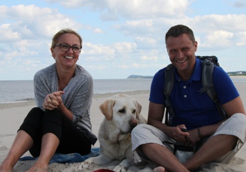 Dogsharing-Plattform Titelbild / Mann und Frau mit Hund am Strand