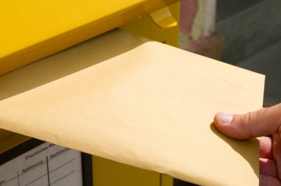 Einwurf eines Briefes in einen Briefkasten.