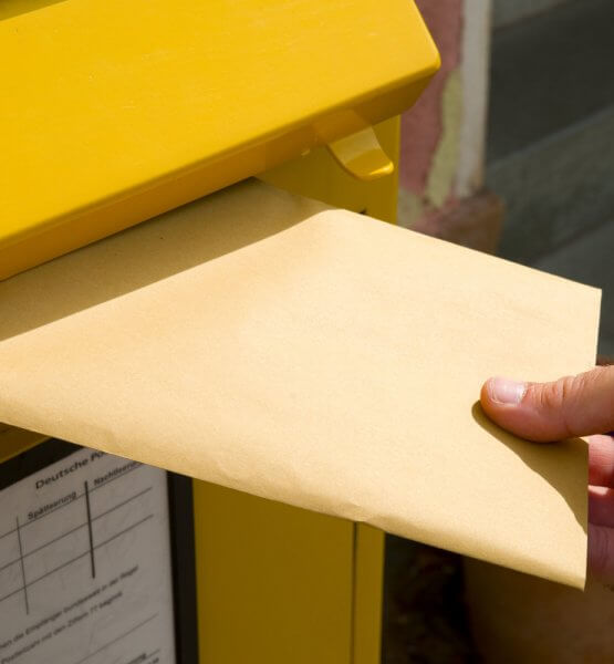 Einwurf eines Briefes in einen Briefkasten.
