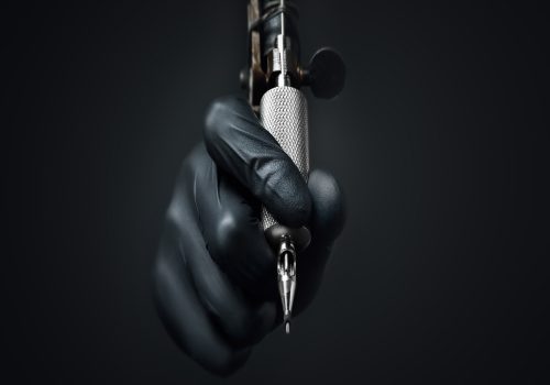 Eine Hand, die eine Tätowiermaschine hält.