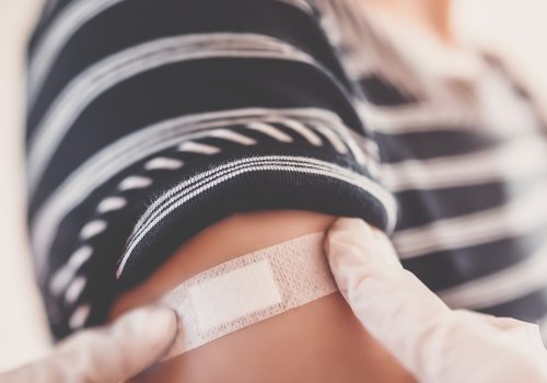 Ein Pflaster wird nach dem Impfen auf den Arm einer Person geklebt.