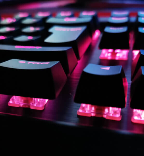Nahaufnahme einer mechanischen Tastatur, dessen Tasten magentafarben beleuchtet werden.