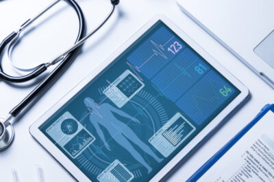 Beitragsbild Elektronische Patientenakte: Stethoskop, Tablet, Laptop und Fragebogen auf einem weißen Tisch.