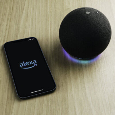 Ein smarter Lautsprecher Amazon Echo und ein Smartphone mit geöffneter Alexa-App.