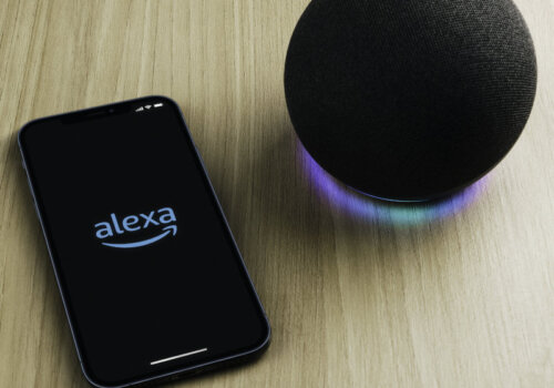 Ein smarter Lautsprecher Amazon Echo und ein Smartphone mit geöffneter Alexa-App.