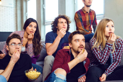 Eine Gruppe von Freunden verfolgt gespannt zusammen einen Film und essen Popcorn.