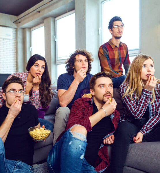 Eine Gruppe von Freunden verfolgt gespannt zusammen einen Film und essen Popcorn.