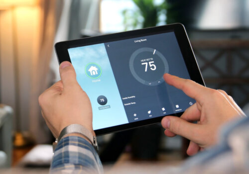 Beitragsbild: Mann passt eine Temperatur mit einem Tablet mit Smart-Home-App im modernen Wohnzimmer an.