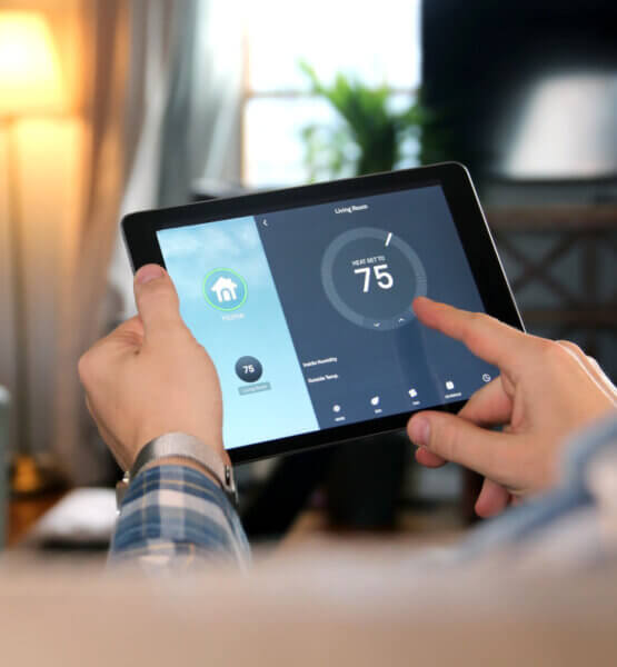Beitragsbild: Mann passt eine Temperatur mit einem Tablet mit Smart-Home-App im modernen Wohnzimmer an.