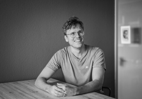 Jonas Thiemann an einem Tisch, er lächelt an der kamera vorbei