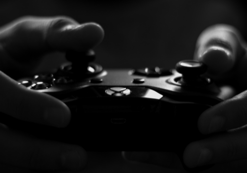 Titelbild zu "Was soll ich spielen?" zwei Händen halten einen XBox Controller - Schwarz weiß Foto von lalesh aldarwish von Pexels