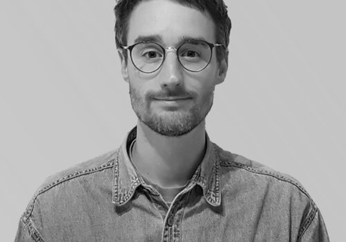 Julian Adenauer im Portraitfoto von vorn, er trägt ein Hemd und eine Brille