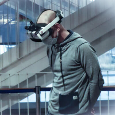 Ein Mann, der Maske und VR-Brille in seiner Arbeitsumgebung trägt.