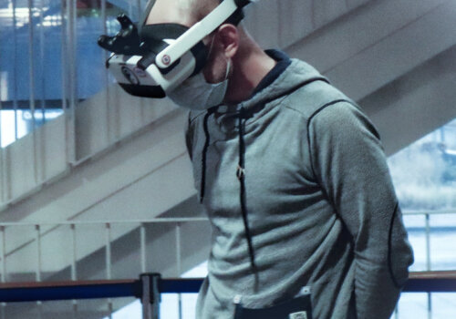 Ein Mann, der Maske und VR-Brille in seiner Arbeitsumgebung trägt.