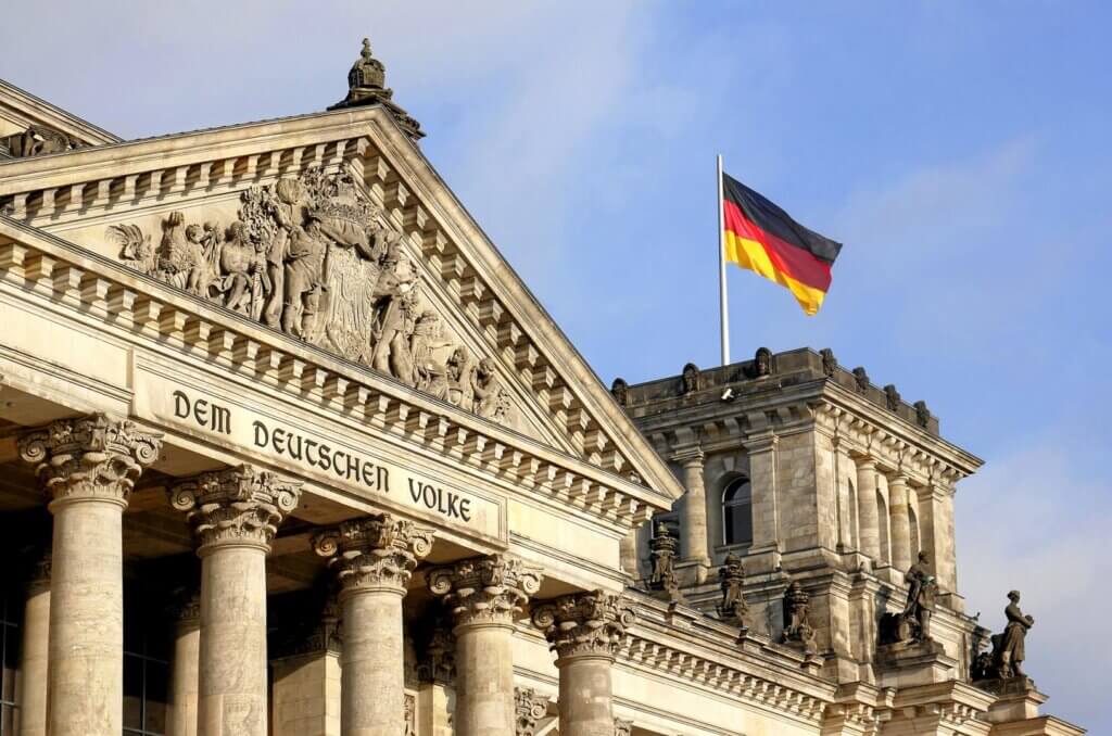 Blick auf das Reichstaggebäude, auf dem eine deutsche Fahne weht.