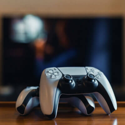 Zwei Playstation 5 (PS5) Controller zu Hause, Fernseher im Hintergrund