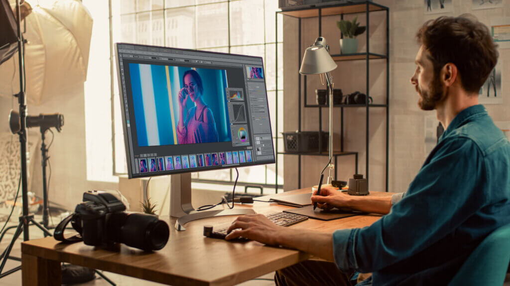 Ein Mann sitzt am PC und bearbeitet ein Foto mit einem Bildbearbeitungsprogramm