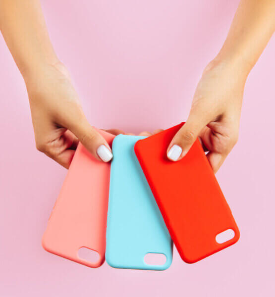 Zwei Hände halten drei verschiedenfarbige Handyhüllen ausgefächert zur Auswahl hin.