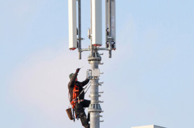 Ein Arbeiter in luftiger Höhe werkelt an einem Mobilfunkmast.