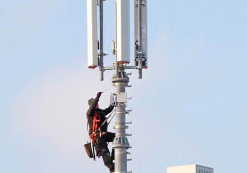 Ein Arbeiter in luftiger Höhe werkelt an einem Mobilfunkmast.