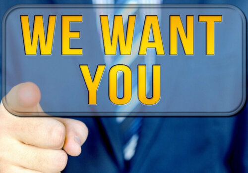 Ein Mann im Anzug zeigt mit dem Zeigefinger zum Bildschirm. Dazu ein eingerahmter Schriftzug "We want you"