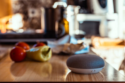 Eine Arbeitsfläche in der Küche mit frischen Zutaten und einem smarten Sprachassistenten.