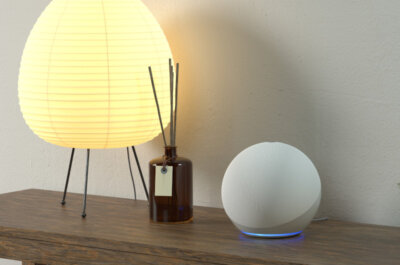 Ein Amazon-Echo auf einem Regal, zusammen mit einer gemütlichen Lampe und Duftstäbchen