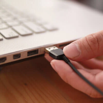 Beitragsbild 7 lustige USB-Gadgets: Nahaufnahme einer Hand, die das Datenkabel in den USB-Anschluss einsteckt