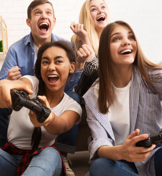 Vier Personen spielen auf einer Spielekonsole und haben dabei sehr viel Spaß.