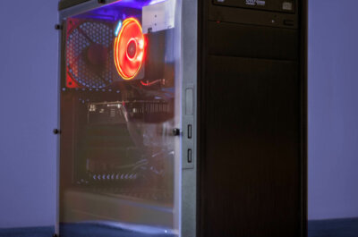 Ein PC vor dunkelblauen Hintergrund. Der PC hat eine durchsichtige Seite, wordurch man die Teils beleuchteten Komponenten sehen kann.