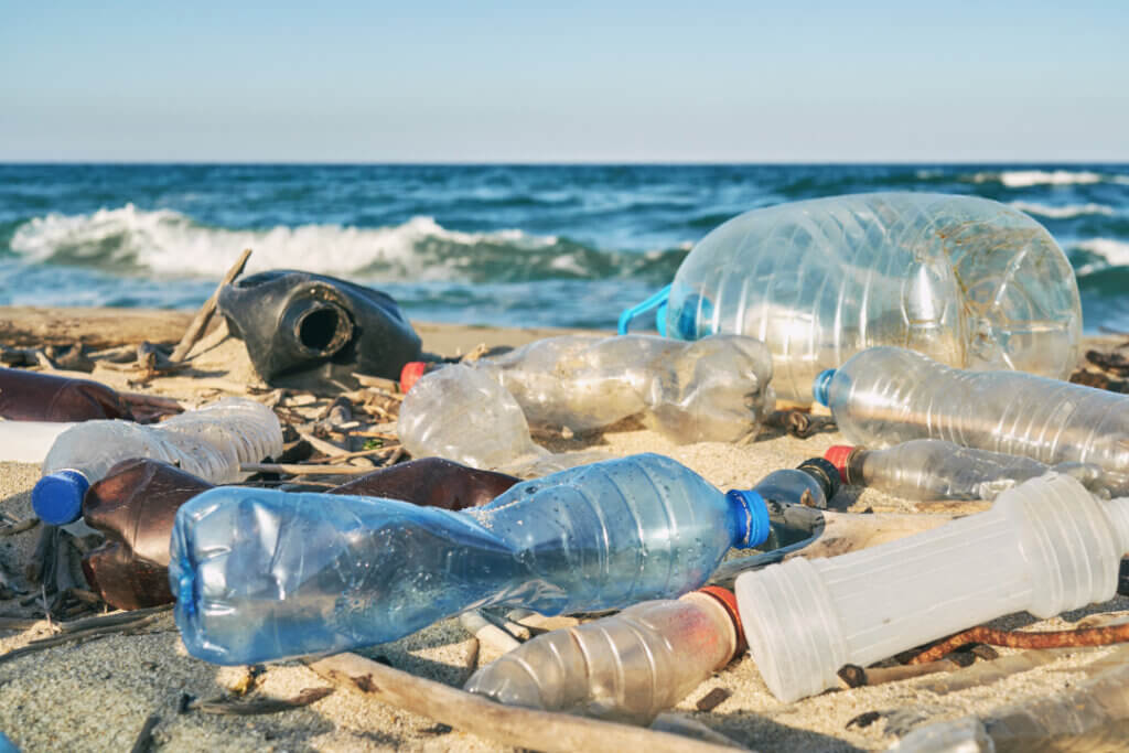 Plastikmüll in Form von leeren Flaschen auf einem Strandabschnitt. 