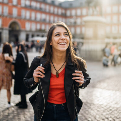 Eine junge Frau schaut sich begeistert auf dem Plaza Mayor in Barcelona um.