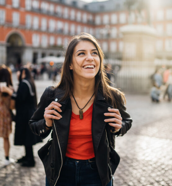 Eine junge Frau schaut sich begeistert auf dem Plaza Mayor in Barcelona um.