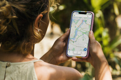 Eine Frau orientiert sich im sonnigen Rio de Janeiro mit Google Maps auf dem Smartphone.