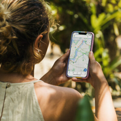 Eine Frau orientiert sich im sonnigen Rio de Janeiro mit Google Maps auf dem Smartphone.