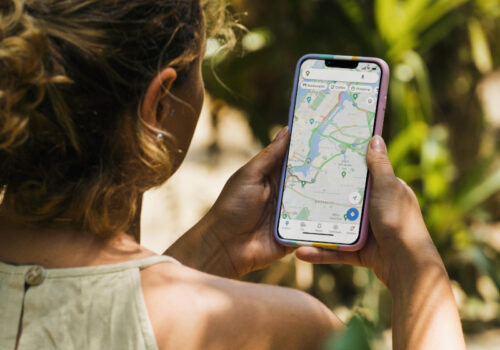 Eine Frau orientiert sich im sonnigen Rio de Janeiro mit Google Maps auf dem Smartphone.