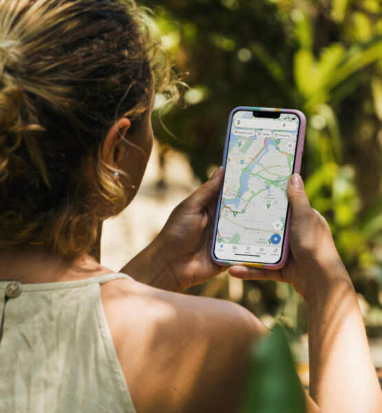 Eine Frau orientiert sich im sonnigen Rio de Janeiro mit Google Maps auf dem Smartphone.