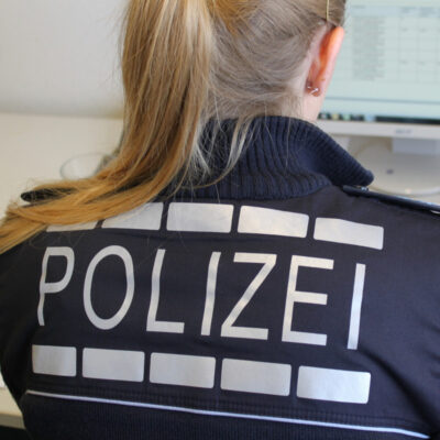 Eine Polizistin sitzt im Büro am Computer.